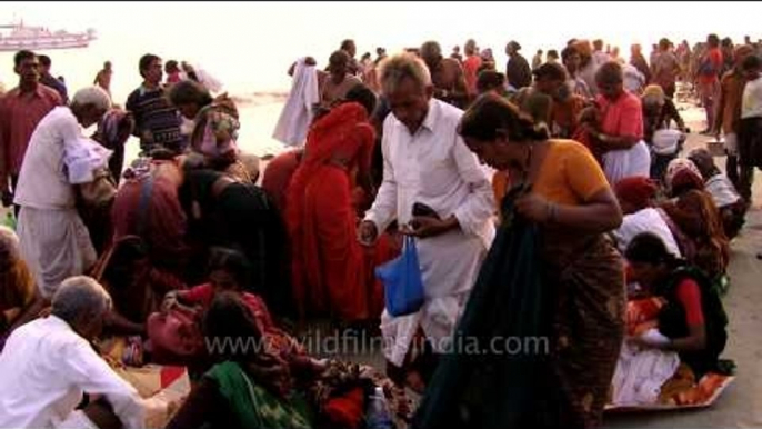 Indian pilgrims putting their clothes on after a holy dip