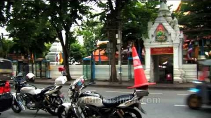 Roadside temple, tuk-tuks and traffic in Bangkok city