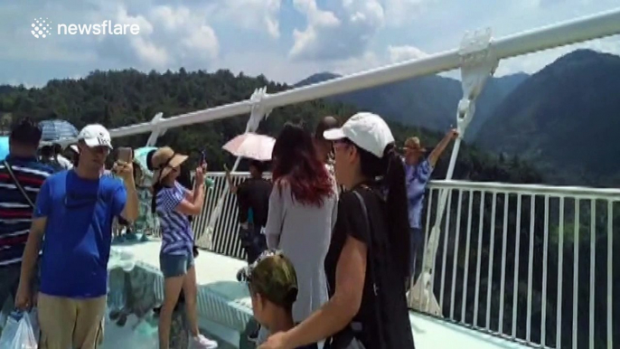 Thousands of tourists walk on the world's longest and highest glass-bottomed bridge