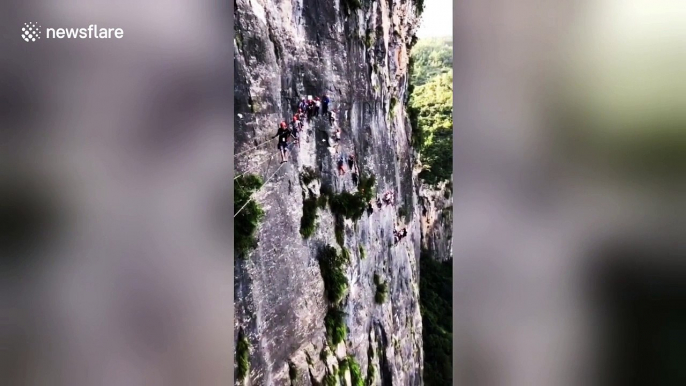 Daredevil tourists climb on a vertical cliff in central China