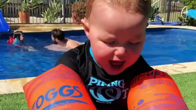 Baby attempts to eat banana while wearing floaties