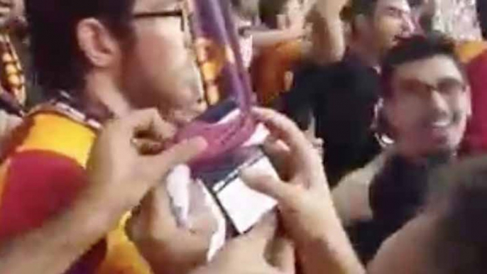 Un supporter du Galatasaray fait tomber son téléphone et le remonte à l'aide de plusieurs écharpes