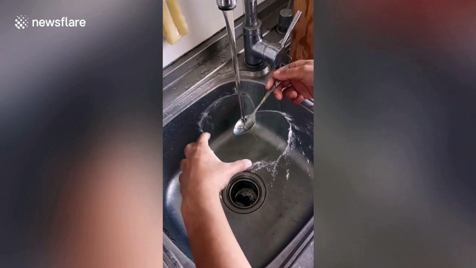 Chinese woman forms heart shape out of running water with a spoon