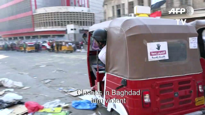 Iraqi protesters run to safety during clashes with riot police in Baghdad