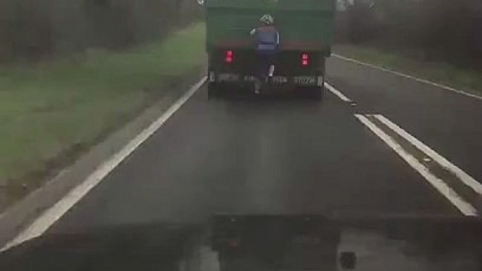 Cyclist Hitching a Ride Holding onto a Truck