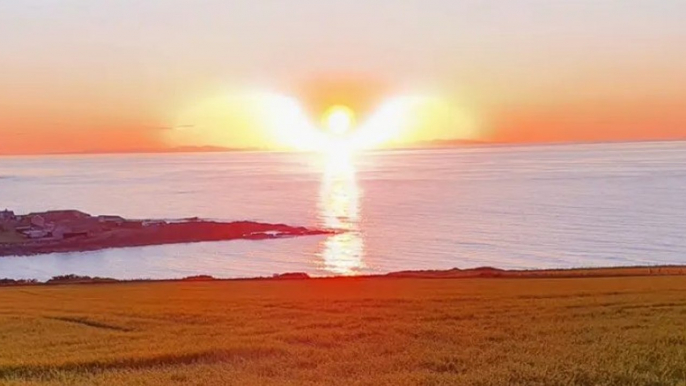 Sur cette photo unique, le soleil et la mer prennent la forme d'un ange avec des ailes pendant un coucher de soleil