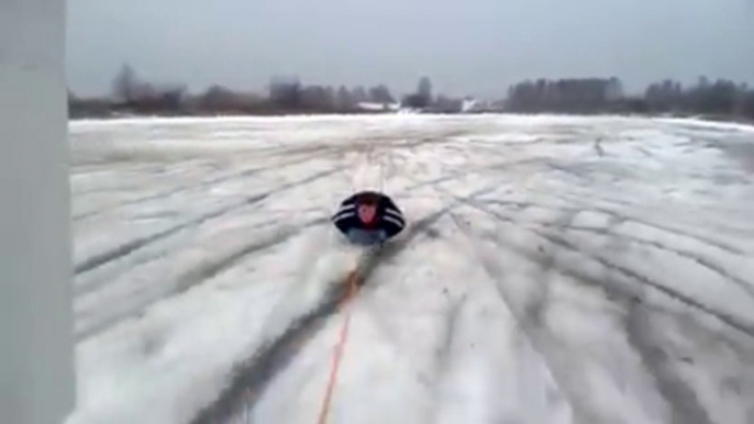 A car pulls a guy lay on the snow! Crazy dumb guy!