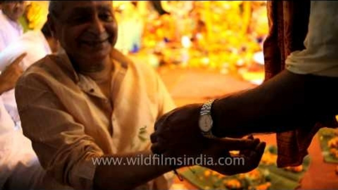 Tying holy leaf around devotees hand: Kolkata Durga puja