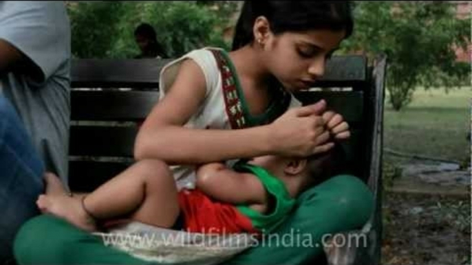 Girl feeding infant with a milk bottle