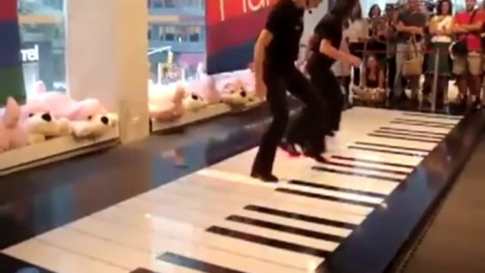 Two people playing Toccata in D Minor on a floor giant piano.