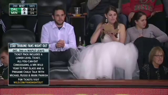 Une mariée en robe fan de NHL mange un burger dans les tribune pendant un match de Hockey... Insolite