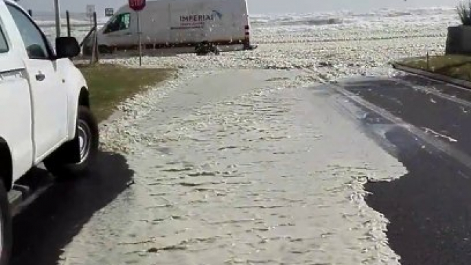 Une route de bord de plage recouverte d'écume après une tempête en mer - Afrique du sud