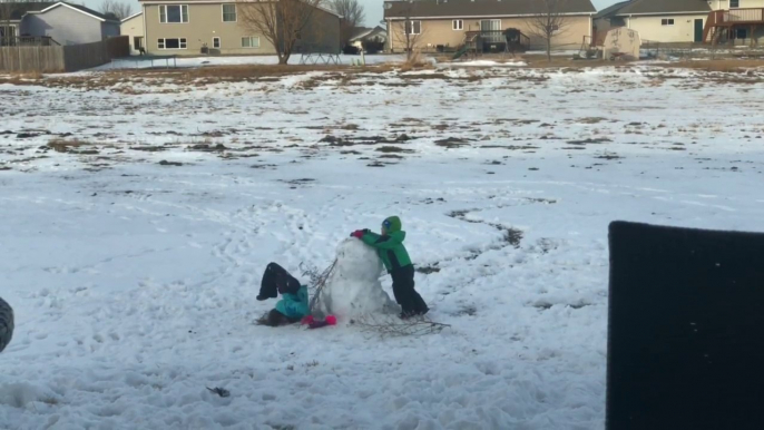 Il aide sa soeur et lui fait manger la neige par la tête !! Joli bonhomme de neige !