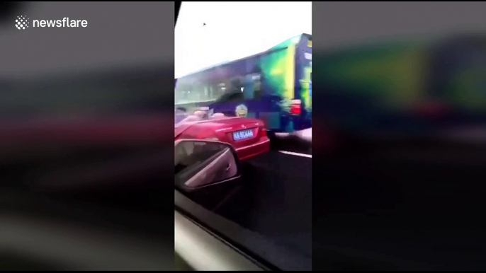 Man holds umbrella while driving convertible in rain