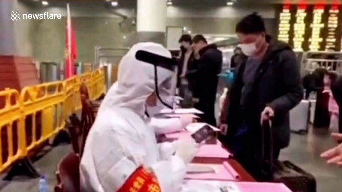 Train station staff in China wear protective clothing to check commuters amid coronavirus outbreak