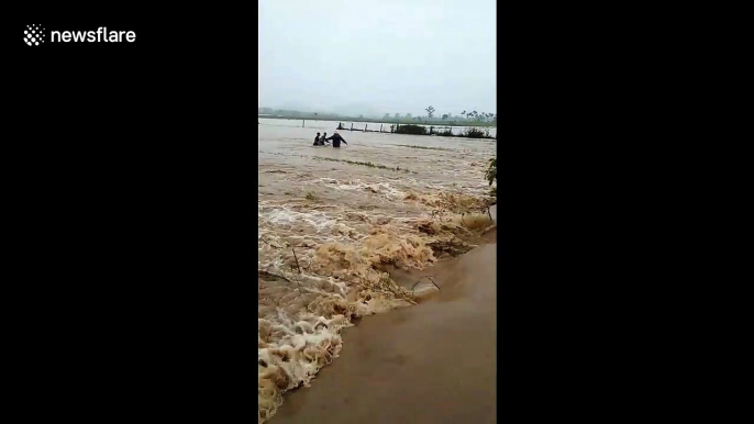 Locals rescue man and his motorbike who were swept away by flash flooding in Vietnam