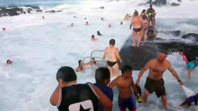 Des touristes surpris par une grosse vague dans une piscine naturelle