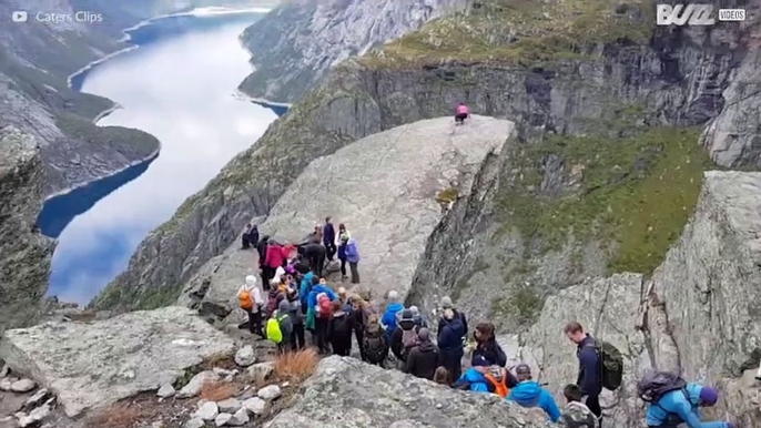 Pessoas fazem fila para tirarem uma foto numa montanha na Noruega