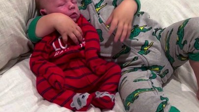 big brother adorably cuddles with newborn baby